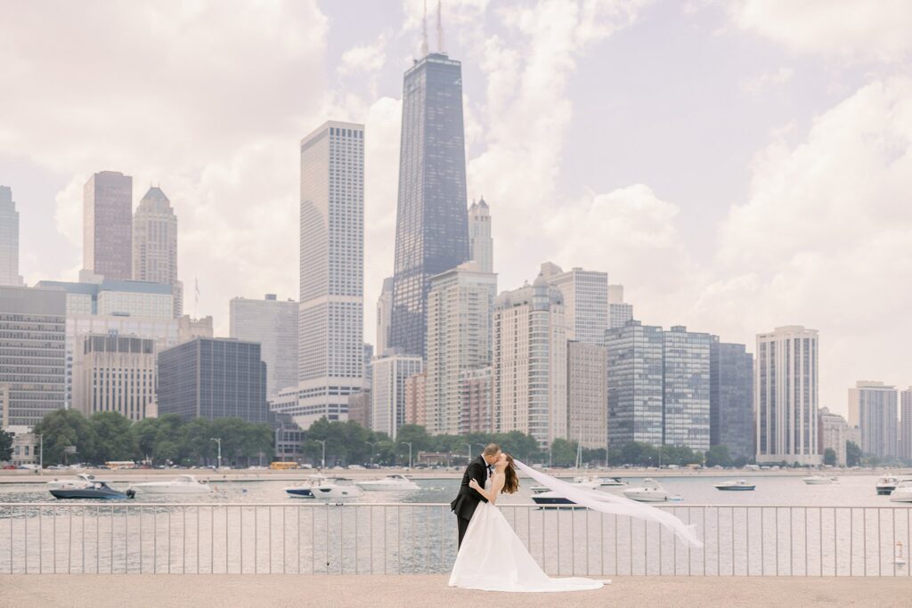 bride and groom kissing in front of chicago skyline before Chicago Winery Wedding