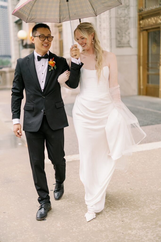 bride and groom caught in the rain share an umbrella