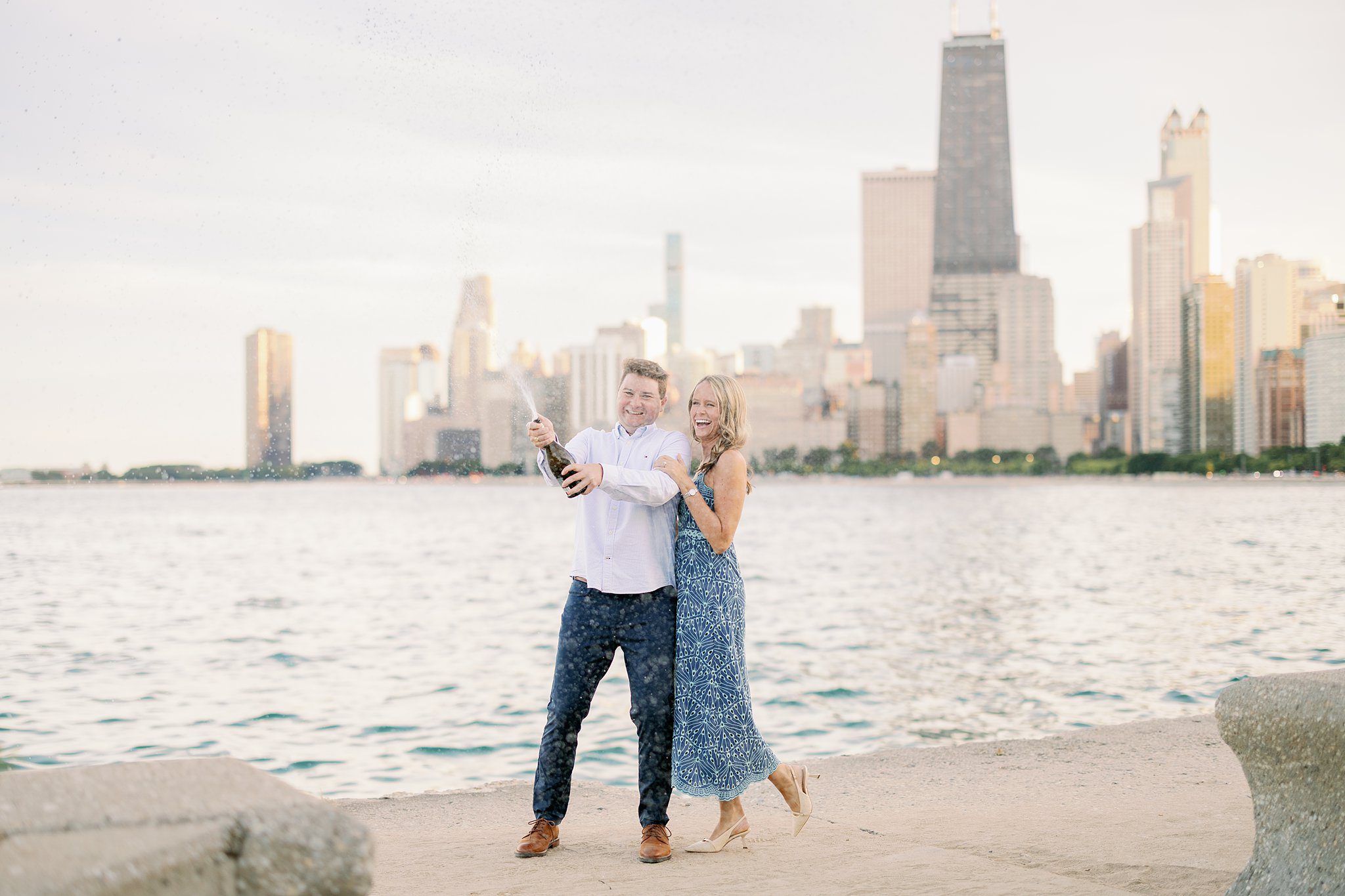 engaged coupe pops champagne at North Avenue Beach in Chicago